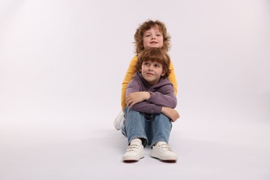 Photo of Cute little brothers posing on white background