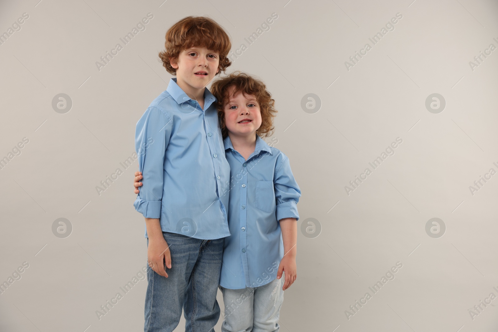 Cute little brothers together on light background. Space for text Photo of Cute little brothers together on light background. Space for text