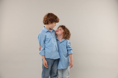 Photo of Cute little brothers hugging on light background