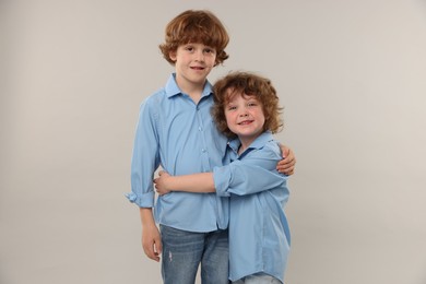 Photo of Cute little brothers hugging on light background