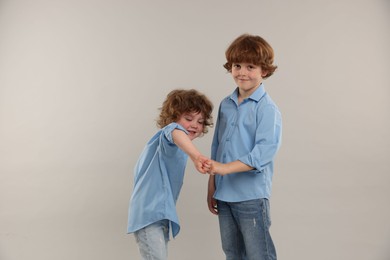 Photo of Cute little brothers bumping fists on light background