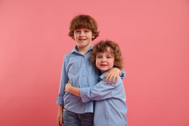 Photo of Cute little brothers hugging on pink background
