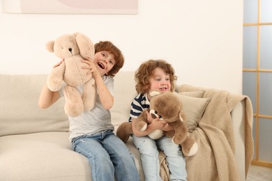 Photo of Cute little brothers playing with toys on sofa at home