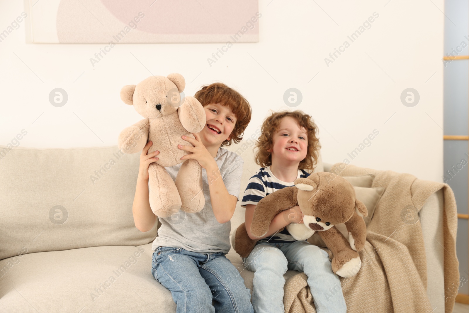 Cute little brothers playing with toys on sofa at home Photo of Cute little brothers playing with toys on sofa at home