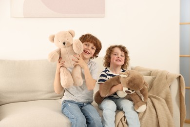 Photo of Cute little brothers playing with toys on sofa at home