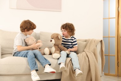 Photo of Cute little brothers playing with toys on sofa at home