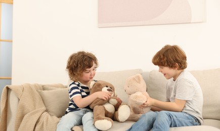 Photo of Cute little brothers playing with toys on sofa at home