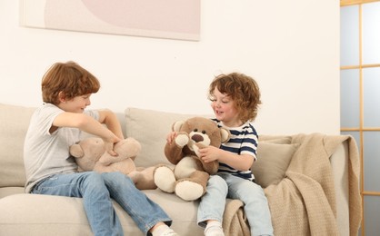 Photo of Cute little brothers playing with toys on sofa at home