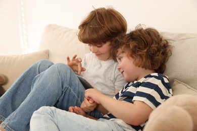 Photo of Cute little brothers with tablet on sofa at home