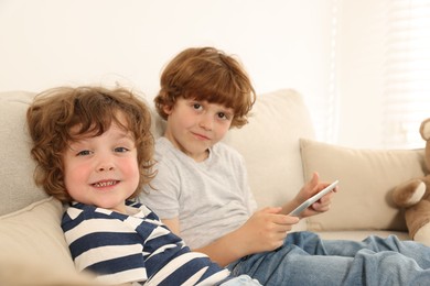Photo of Cute little brothers with tablet on sofa at home