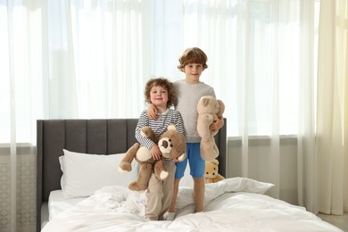 Photo of Cute little brothers with toys on bed at home
