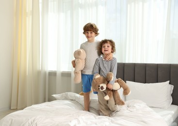 Photo of Cute little brothers with toys on bed at home