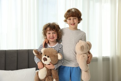 Photo of Cute little brothers with toys on bed at home