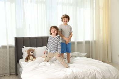 Photo of Cute little brothers on bed at home