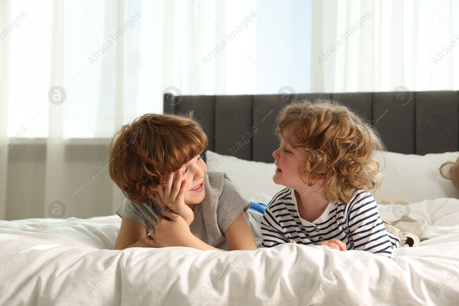 Cute little brothers laying on bed at home Photo of Cute little brothers laying on bed at home