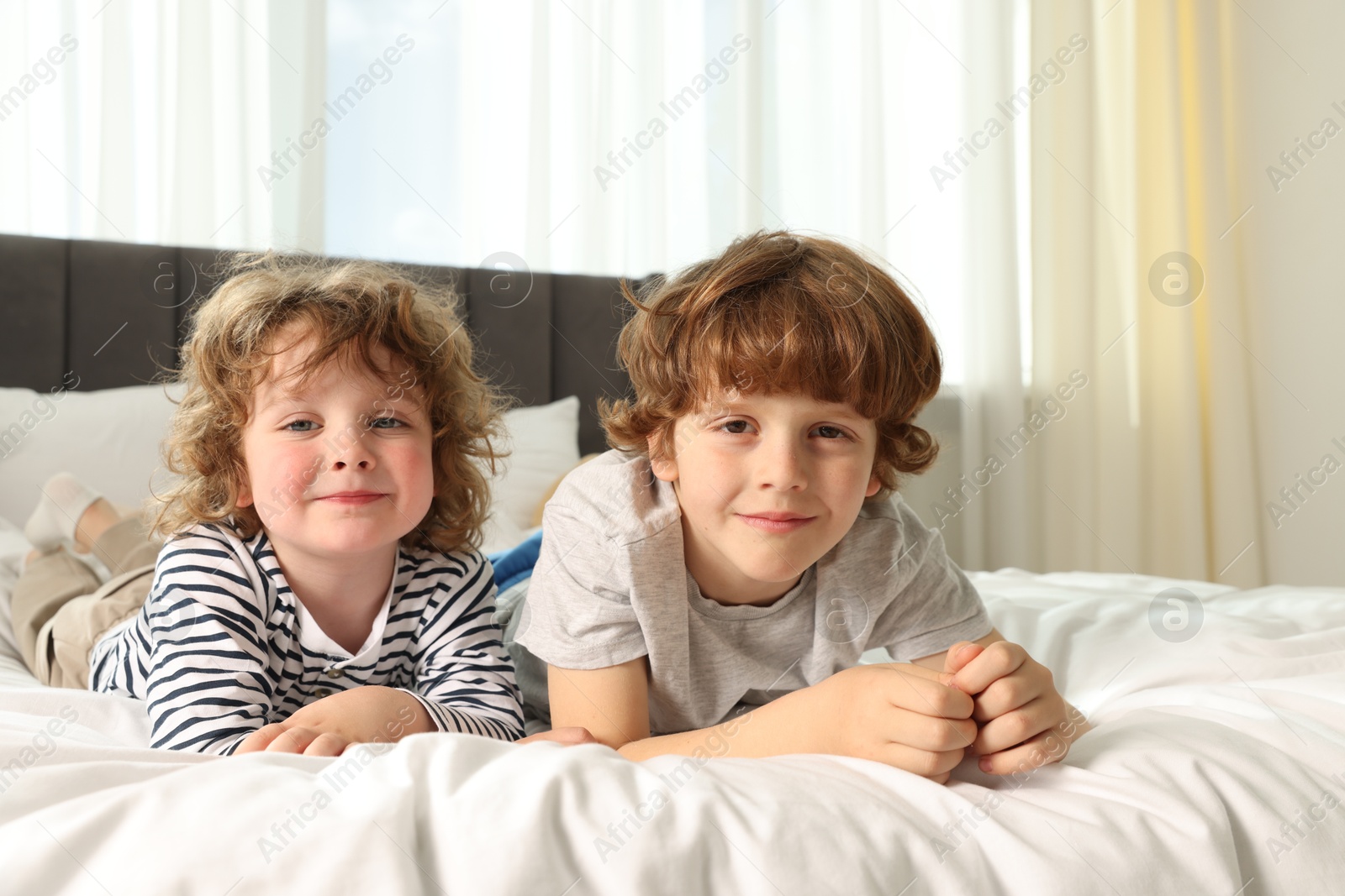 Cute little brothers laying on bed at home Photo of Cute little brothers laying on bed at home