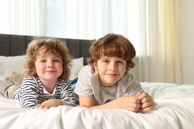 Photo of Cute little brothers laying on bed at home