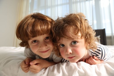 Photo of Cute little brothers laying on bed at home, wide angle