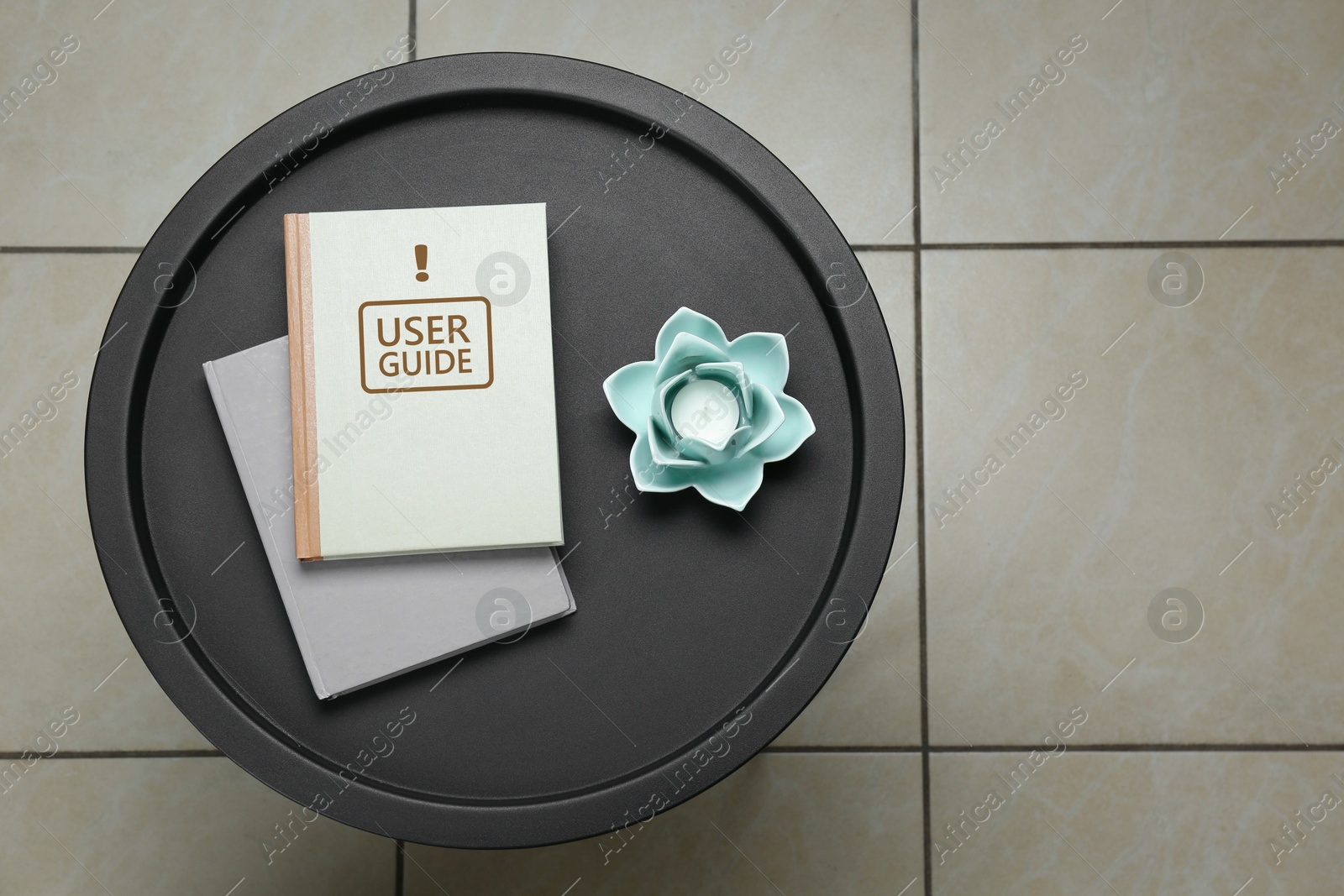 User Guide book and candle holder on table in room, top view Image of User Guide book and candle holder on table in room, top view