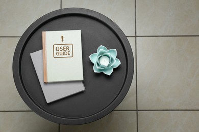 Image of User Guide book and candle holder on table in room, top view