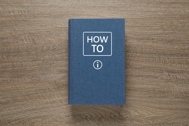 Image of How To book on wooden background, top view. User guide
