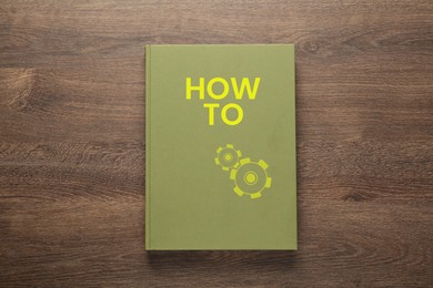 Image of How To book on wooden background, top view. User guide
