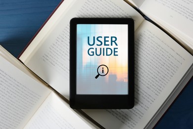 Image of User Guide document open in e-book device and different books on blue wooden table, top view