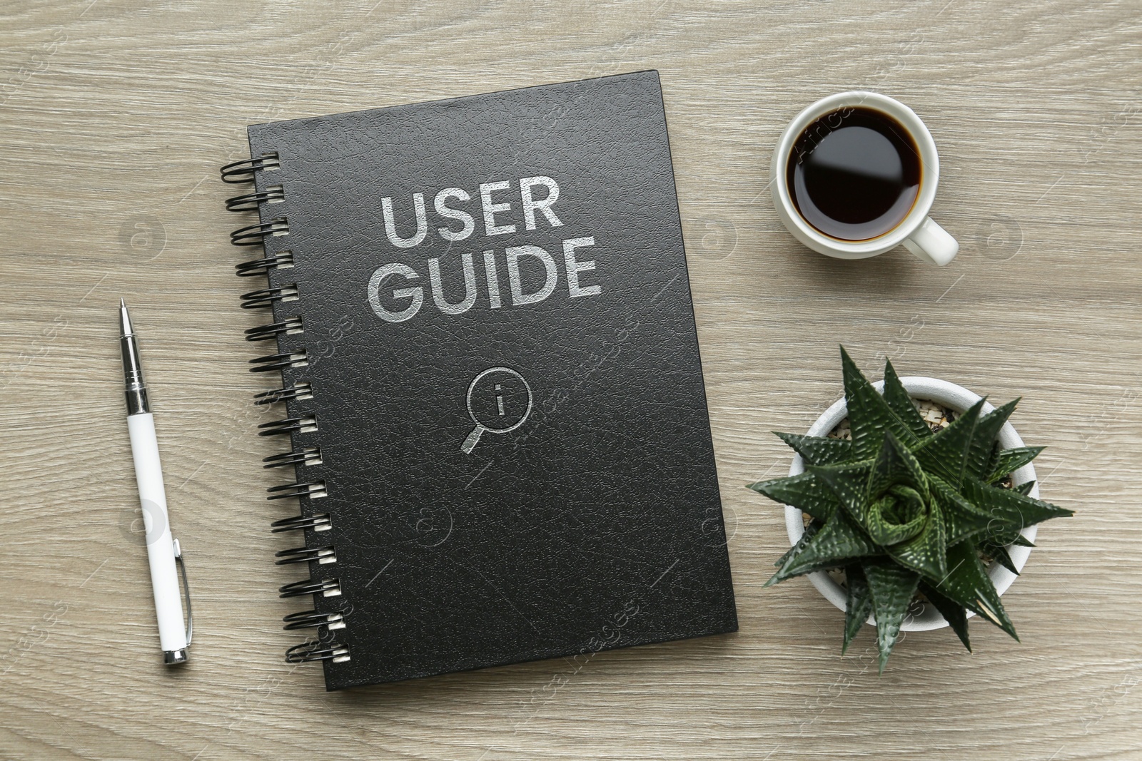 User Guide catalog, cup of coffee, pen and potted plant on wooden table, flat lay Image of User Guide catalog, cup of coffee, pen and potted plant on wooden table, flat lay