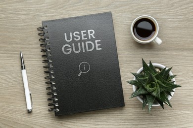 Image of User Guide catalog, cup of coffee, pen and potted plant on wooden table, flat lay
