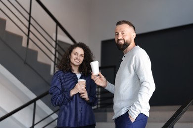 Photo of Colleagues with coffee on stairs in office during break