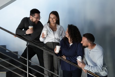Photo of Colleagues with coffee on stairs in office during break