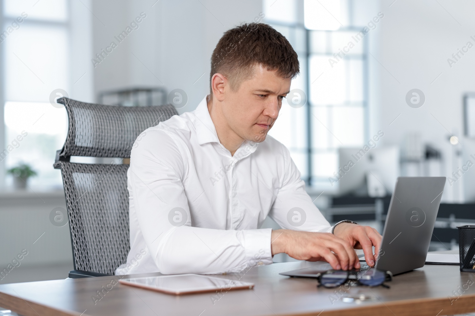 Photo of Man working on laptop at desk in office