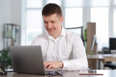Photo of Man working on laptop at desk in office