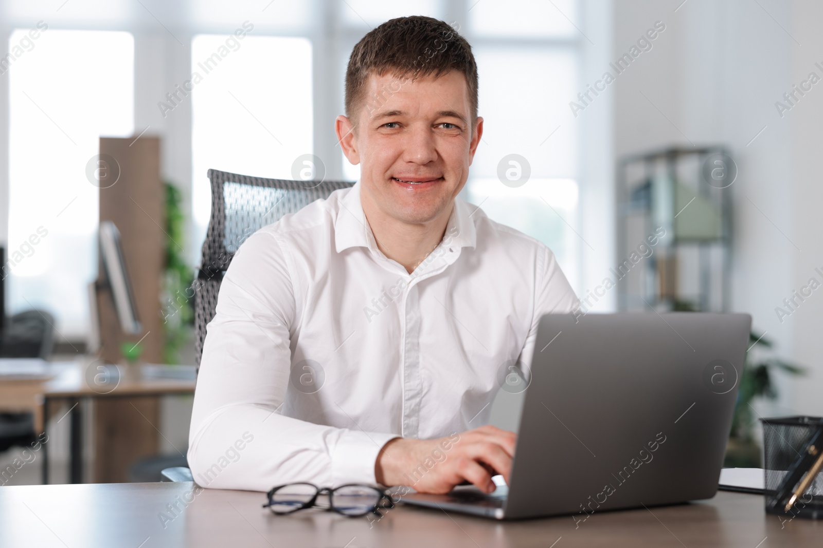 Man working on laptop at desk in office Photo of Man working on laptop at desk in office