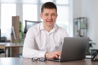 Photo of Man working on laptop at desk in office