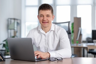 Photo of Man working on laptop at desk in office