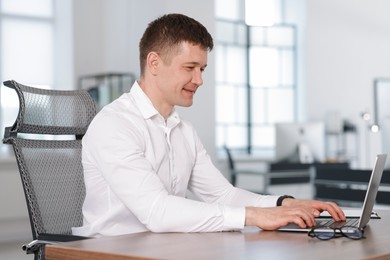 Photo of Man working on laptop at desk in office. Space for text