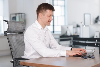 Photo of Man working on laptop at desk in office