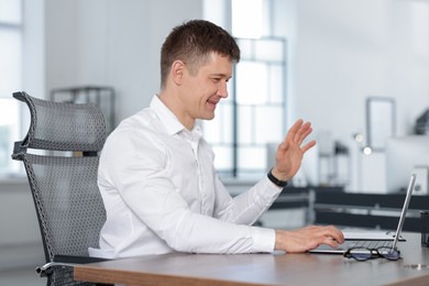 Photo of Man having video call via laptop at desk in office