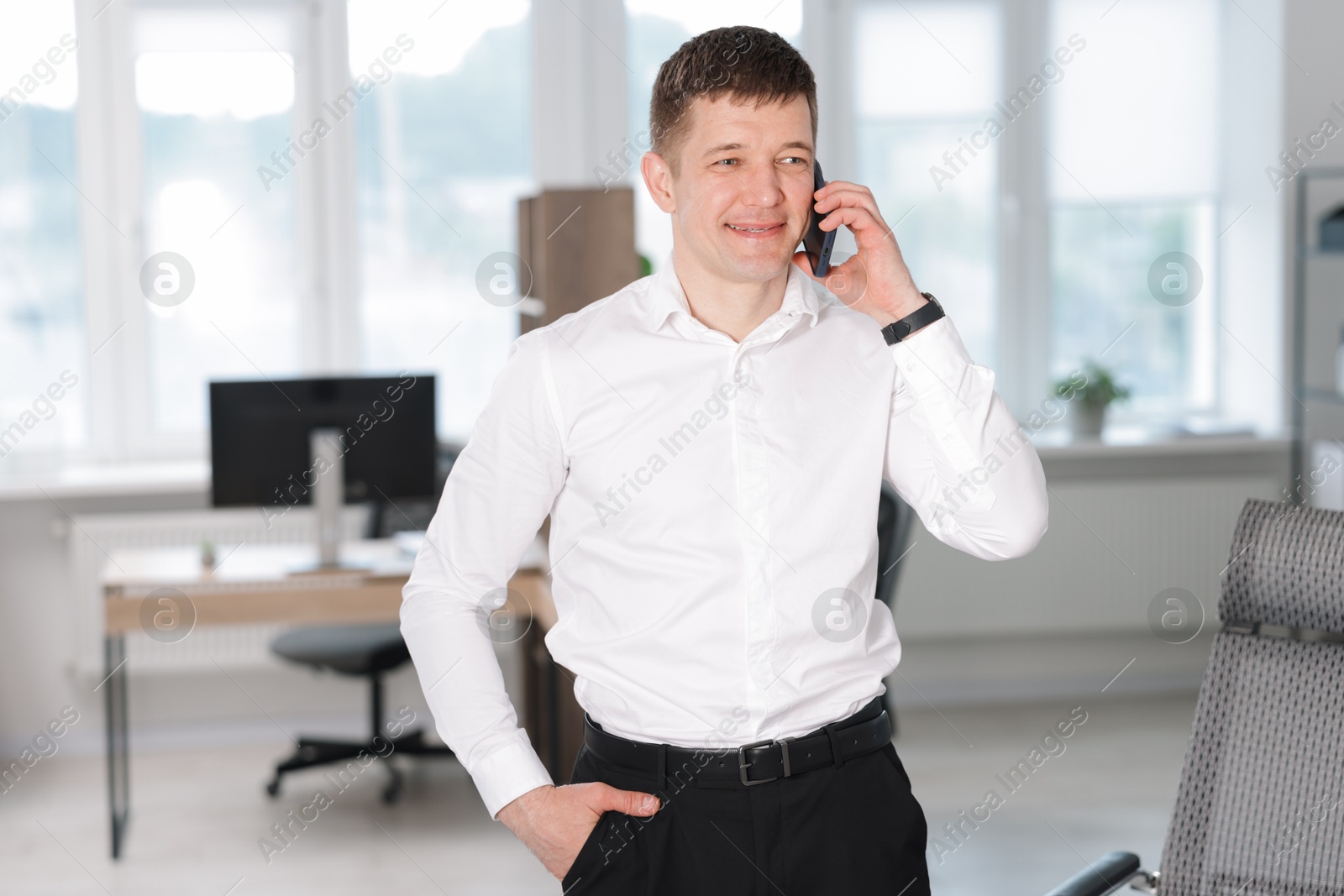 Handsome man talking on phone in office Photo of Handsome man talking on phone in office