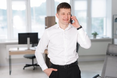 Photo of Handsome man talking on phone in office