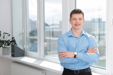 Photo of Portrait of handsome man near window indoors. Space for text