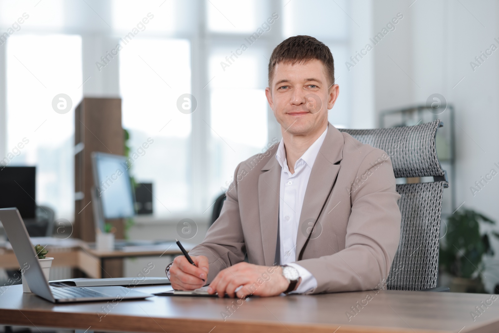 Handsome man working at desk in office. Space for text Photo of Handsome man working at desk in office. Space for text