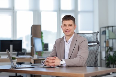 Photo of Portrait of handsome man at desk in office. Space for text