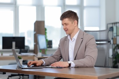 Photo of Man working on laptop at desk in office