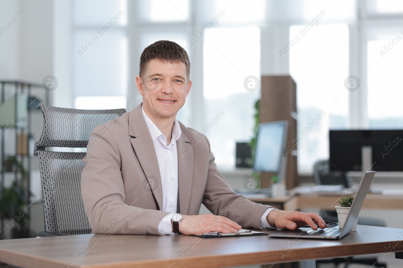 Photo of Man working on laptop at desk in office