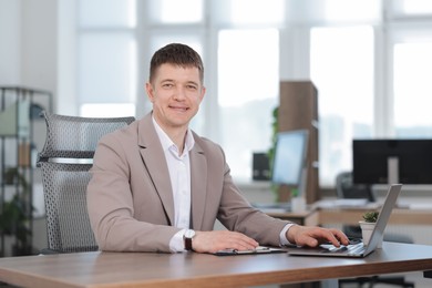 Photo of Man working on laptop at desk in office