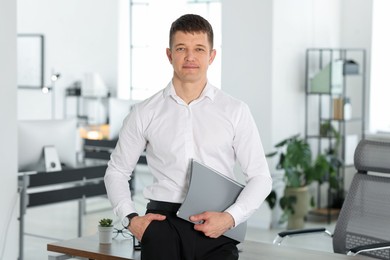 Photo of Portrait of handsome man with folder in office
