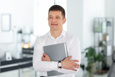 Photo of Portrait of handsome man with folder in office
