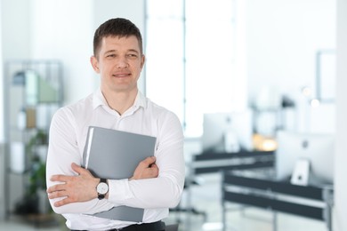 Photo of Portrait of handsome man with folder in office. Space for text